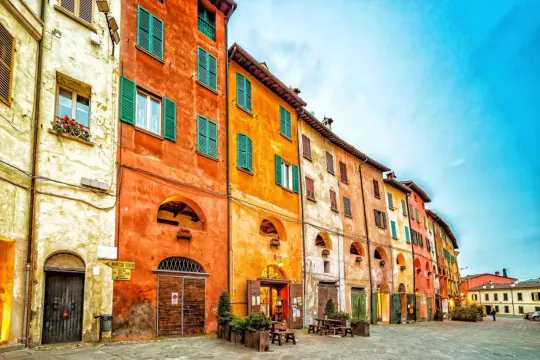Colorate case con persiane verdi e archi si affacciano su una piazza acciottolata. Un assaggio di cosa vedere a Brisighella.