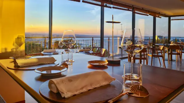 Tavola apparecchiata in un ristorante stellato a Gabicce Monte, con vista sul tramonto sul mare.
