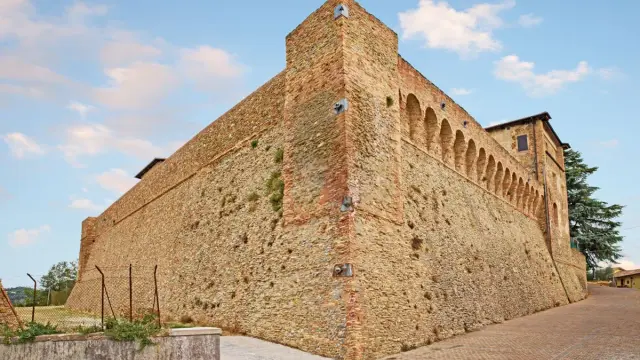 Antica fortezza nella valle del Rubicone, con mura in pietra e mattoni, torri e un loggiato ad archi.