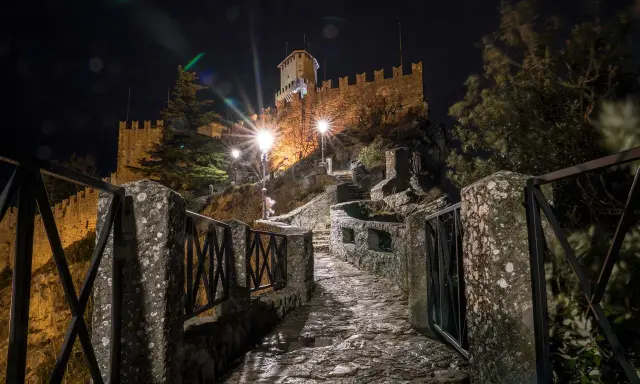 Sentiero lastricato di notte, illuminato da lampioni, conduce verso il castello di San Marino, il passo delle streghe.