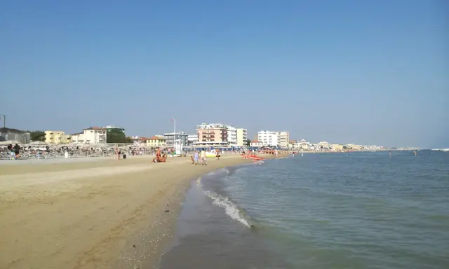 Spiaggia affollata a Viserbella mare, con ombrelloni, lettini e persone che si godono il sole e il mare azzurro sotto un cielo limpido.