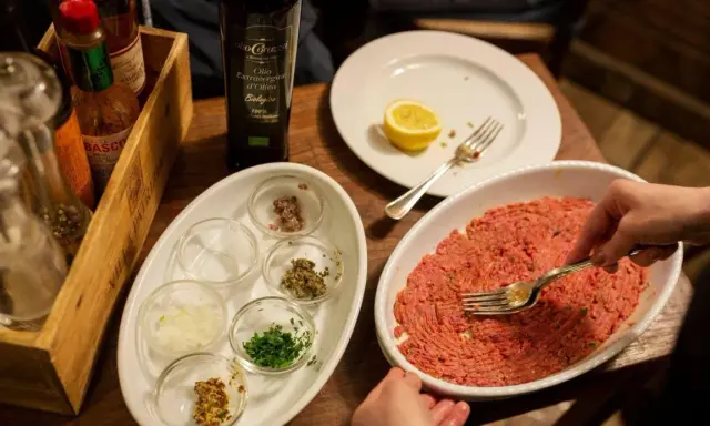 Preparazione di tartare di carne in un ristorante a Rimini, con condimenti e olio EVO.
