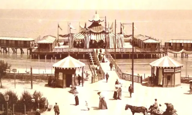 Il primo stabilimento balneare in Italia, un molo con tende a strisce, cabine e gente che passeggia.