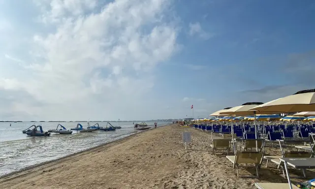 Pedalò in acqua e file di lettini e ombrelloni su una spiaggia sabbiosa, tipica di un bagno Roma di Levante.