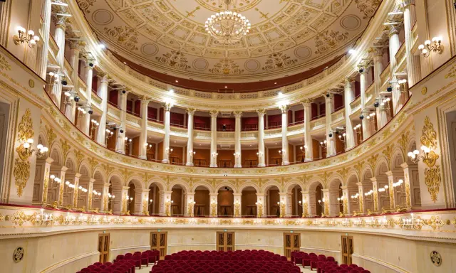 Interni sfarzosi del teatro Amintore Galli, con poltrone rosse e decorazioni dorate. Scopri i prossimi eventi!