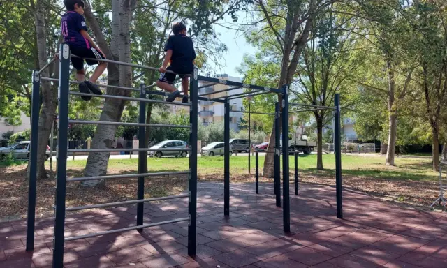 Bambini si arrampicano su una struttura per esercizi all'aperto nel parco Briolini a Rimini.
