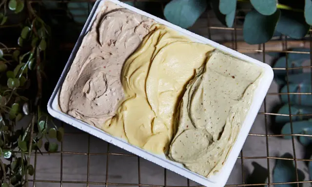 Tre gusti di gelato artigianale, tra cui la romana, in una vaschetta bianca.