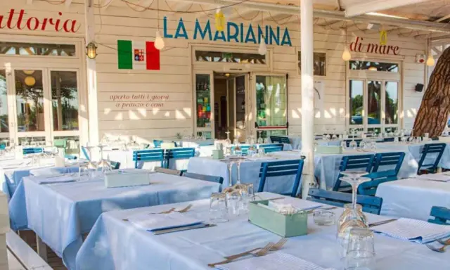 La Marianna Rimini, trattoria sul mare, con tavoli apparecchiati all'esterno sotto un grande albero.