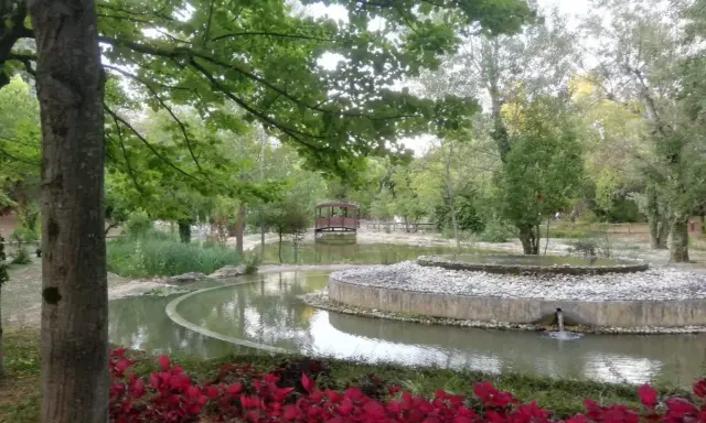 Un laghetto con un ponticello in legno e aiuole fiorite nel Parco della Resistenza a Riccione.