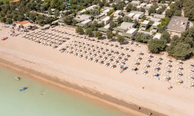 Domenica di sole sulla spiaggia di Rivazzurra, con ombrelloni, lettini e bagnanti che si godono il mare.