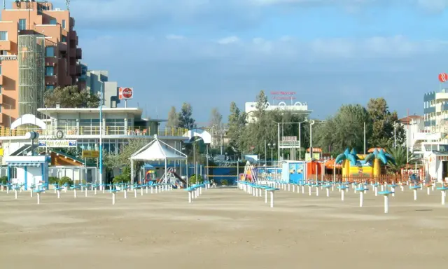 Spiaggia di Rimini a settembre, con ombrelloni chiusi e giochi per bambini in attesa della prossima stagione.