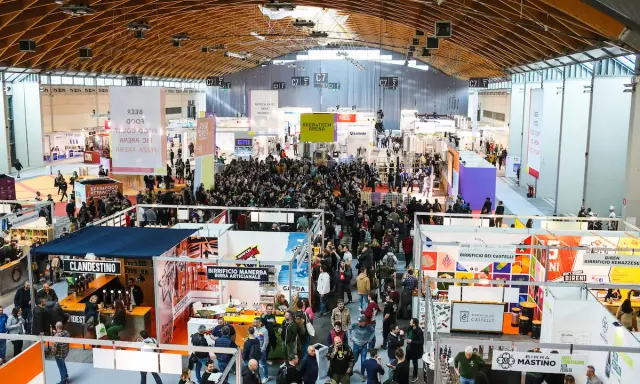 Folla in un padiglione fieristico, un'attrazione beer&food con stand e degustazioni.