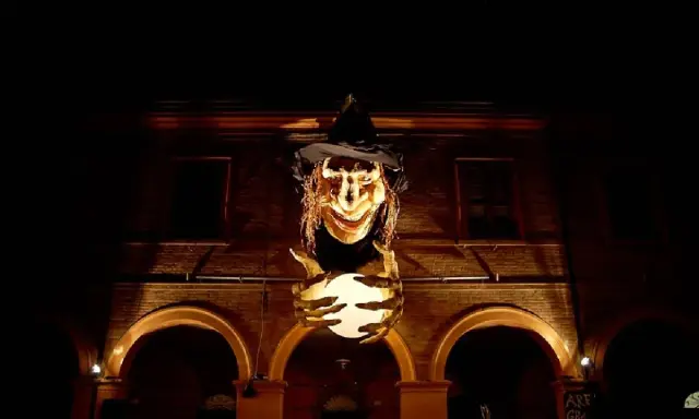 Una strega spaventosa con un cappello nero e una sfera luminosa in mano, illuminata nella notte. Sembra la protagonista de la notte delle streghe.