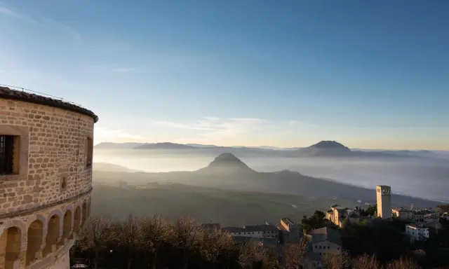 Panoramica di borghi vicino Riccione, con un antico torrione e colline nebbiose all'alba.