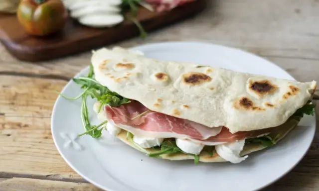 Piadina farcita con prosciutto crudo, mozzarella e rucola. Ecco come si farciscono le piadine per un pasto veloce e gustoso.