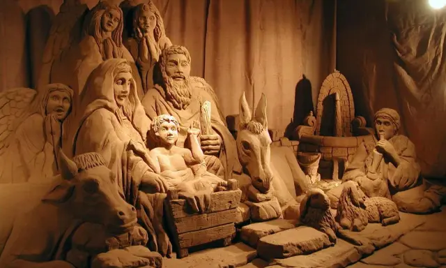 Un suggestivo presepe di sabbia a Rimini, con figure scolpite nella sabbia, tra cui angeli, la Sacra Famiglia, animali e un pastore.