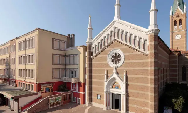 Facciata di una chiesa a Rimini con campanile e edificio adiacente.