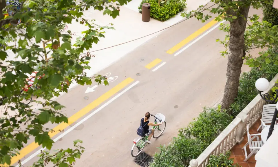 Una donna in bicicletta percorre il lungomare di San Mauro Mare, su una pista ciclabile ben segnalata.