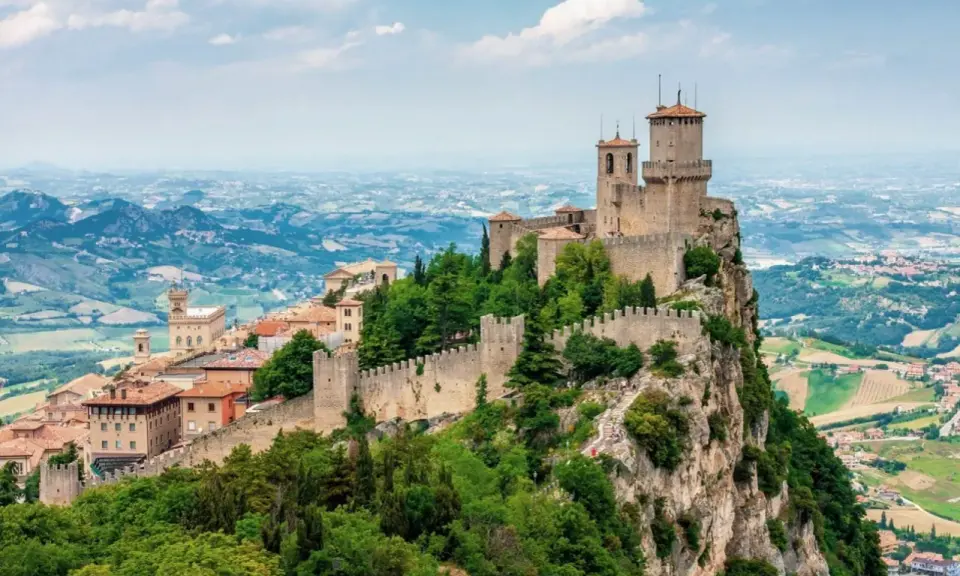Torri medievali su un monte roccioso, con vista panoramica sulla campagna circostante, un paesaggio che ricorda la vicinanza di San Marino a Rimini.