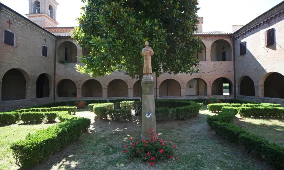 Cortile di una villa a Verucchio con statue, alberi e siepi curate.