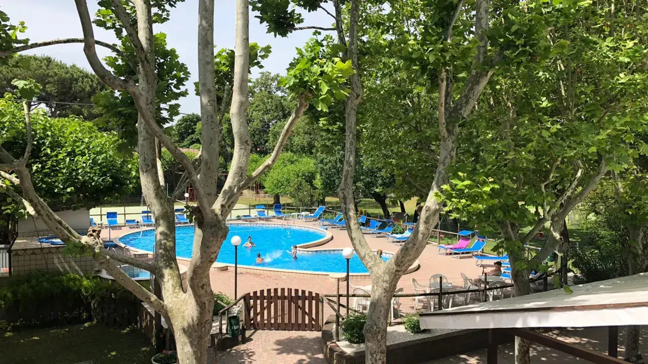 Piscina azzurra e lettini prendisole al **hotel Faro San Mauro Mare**, tra alberi rigogliosi.