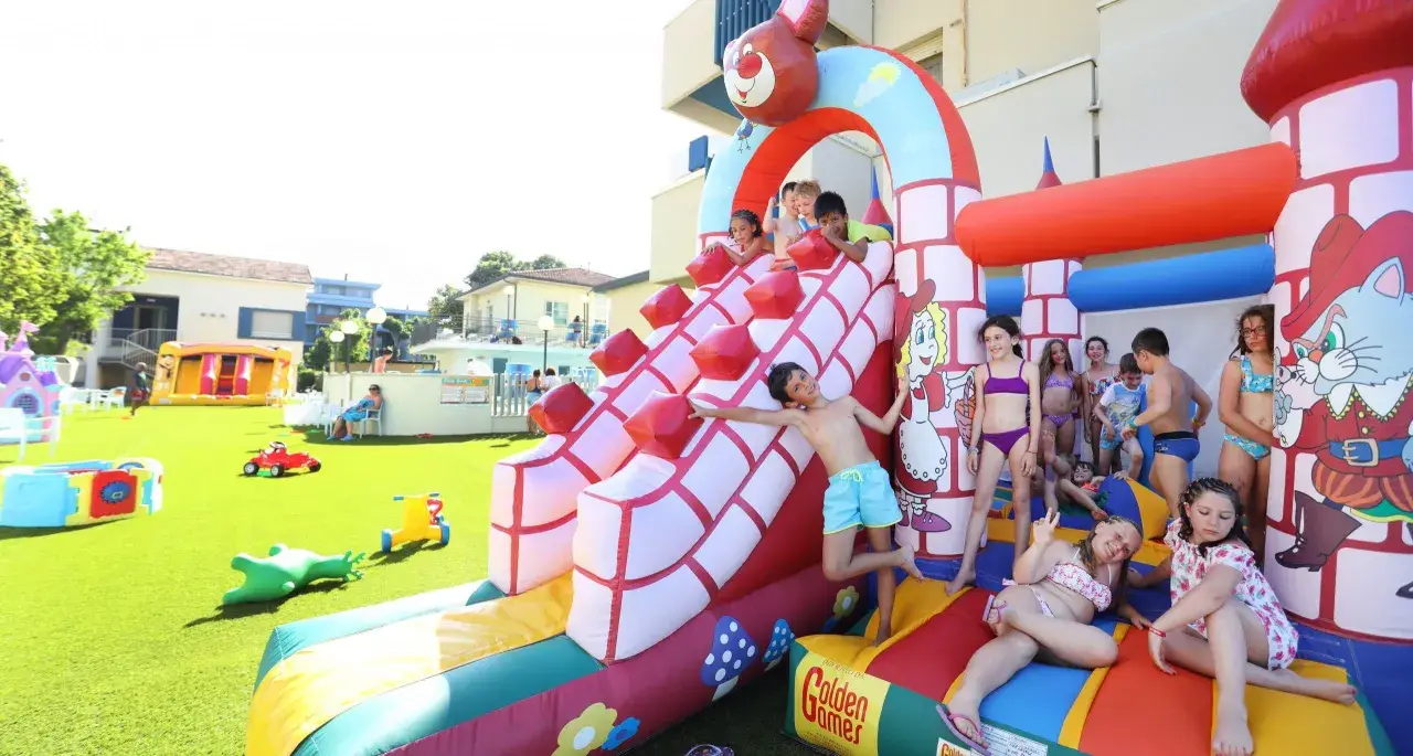 Bambini si divertono sulle giostre gonfiabili a Bellaria, scivolando e giocando in un parco acquatico pieno di allegria.
