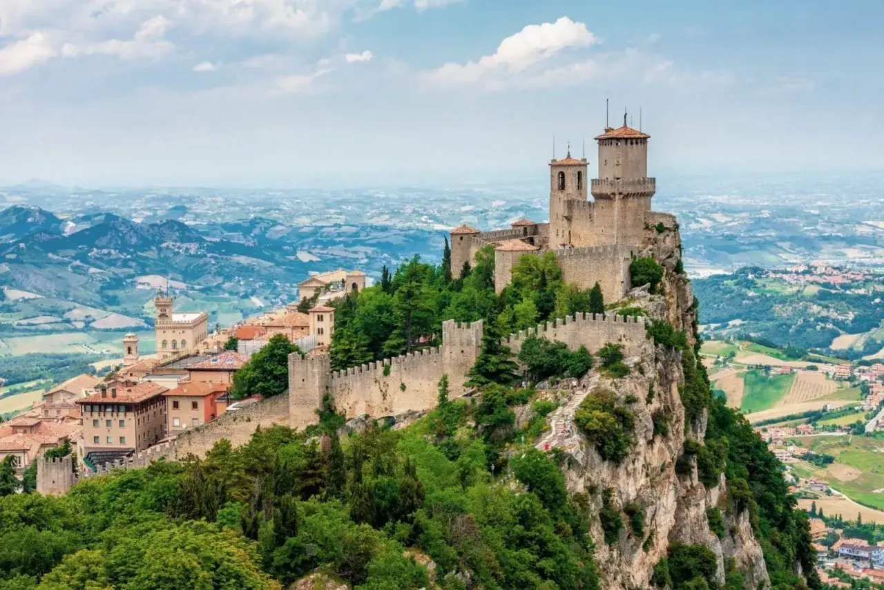Torri medievali su un monte roccioso, con vista panoramica sulla campagna circostante, un paesaggio che ricorda la vicinanza di San Marino a Rimini.