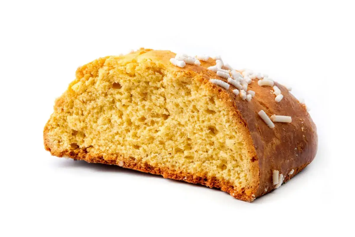 Fetta di ciambella, un dolce tipico romagnolo, con zuccherini bianchi sparsi sulla crosta dorata.