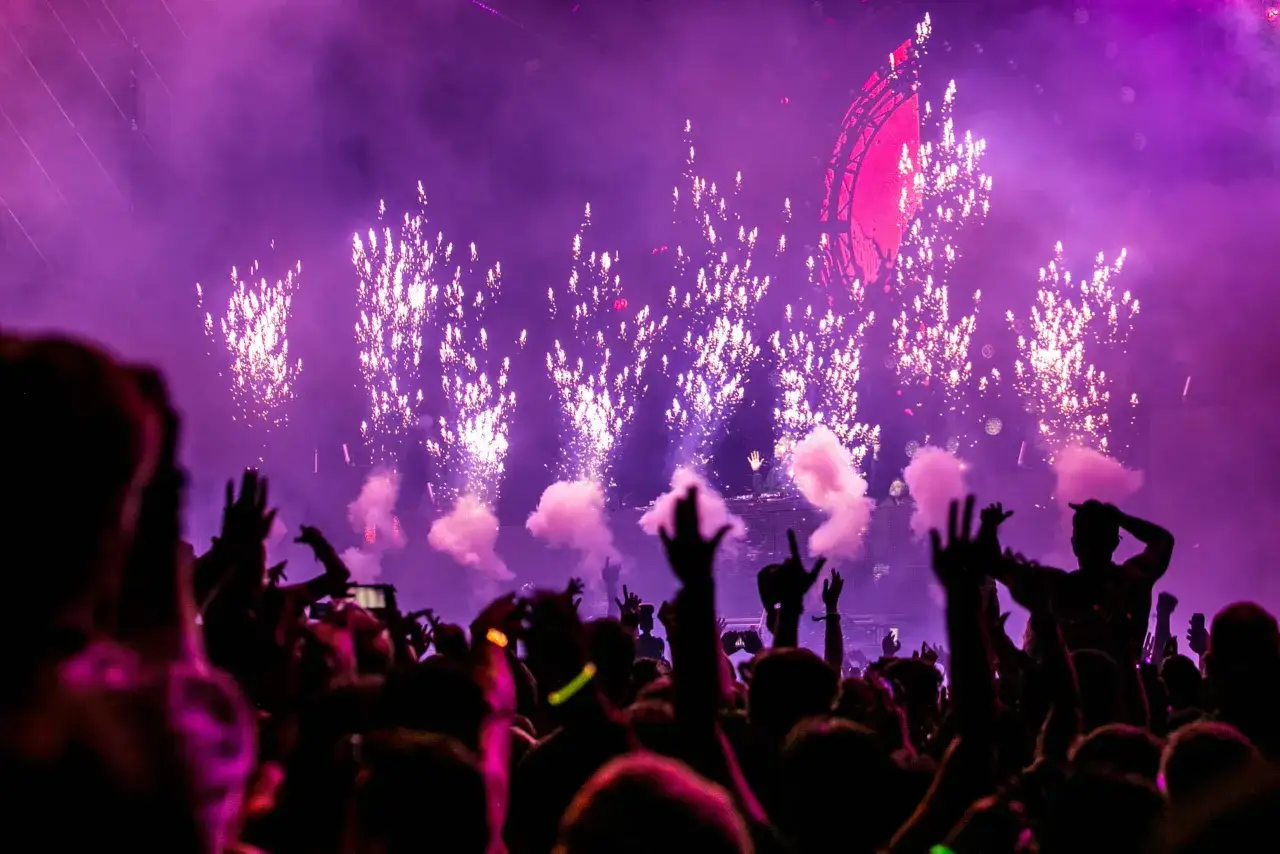 Festa con fuochi d'artificio e fumo rosa in una delle discoteche di Rimini. La folla alza le mani in segno di gioia.