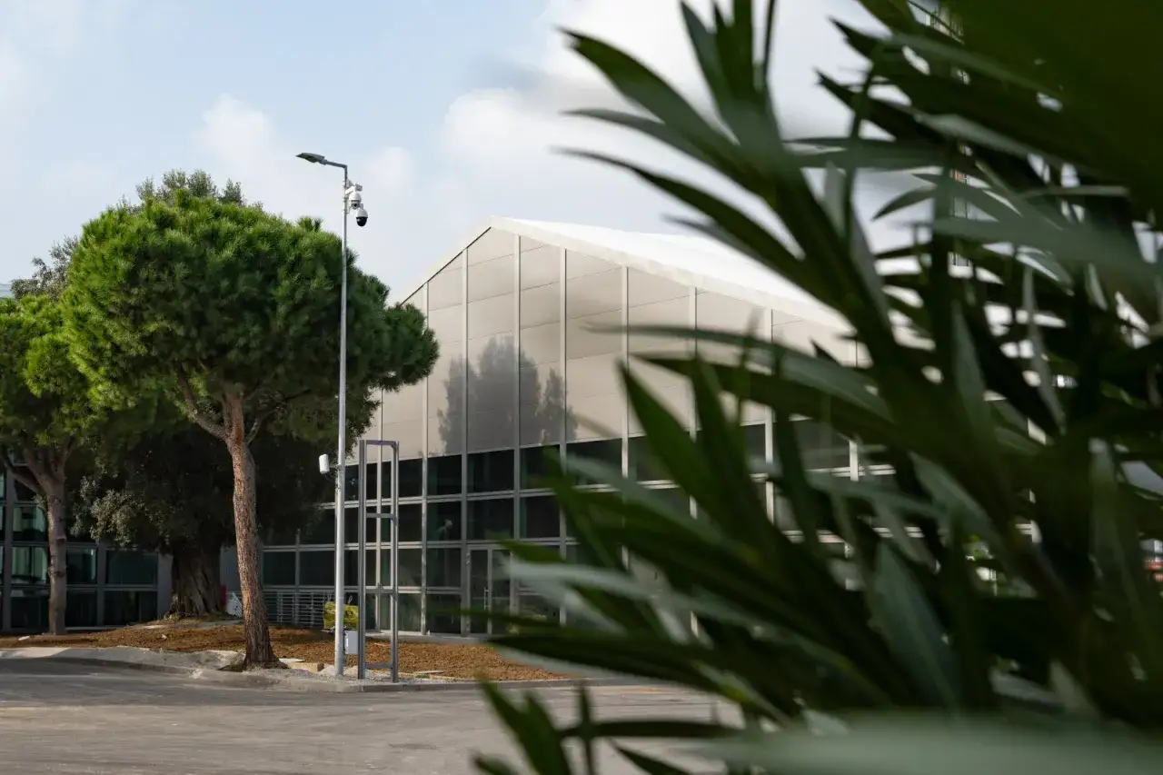 Edificio moderno alla fiera a Rimini, con alberi verdi e fogliame in primo piano.