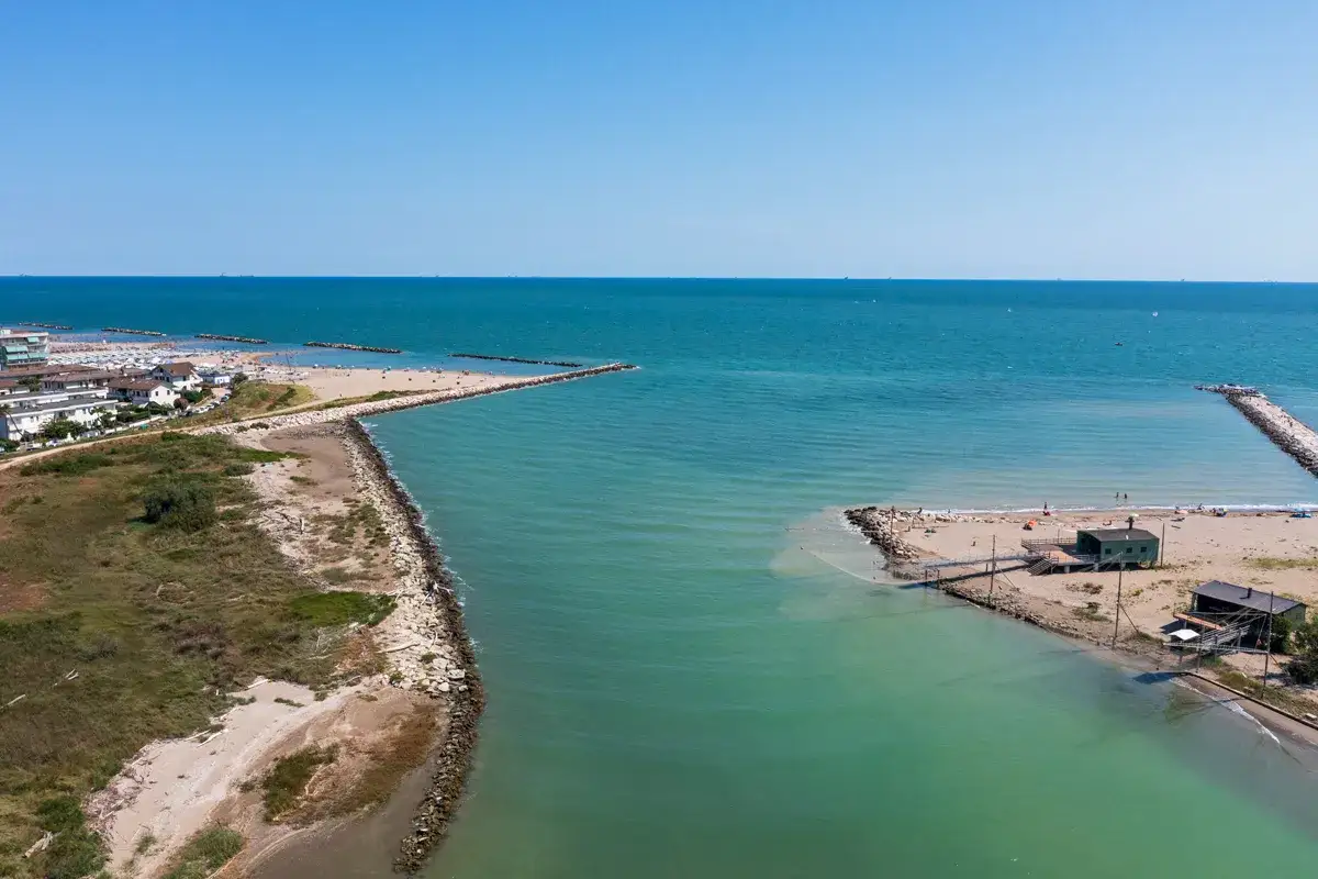 Vista aerea del lido di Savio mare con spiaggia, mare turchese, moli e case.