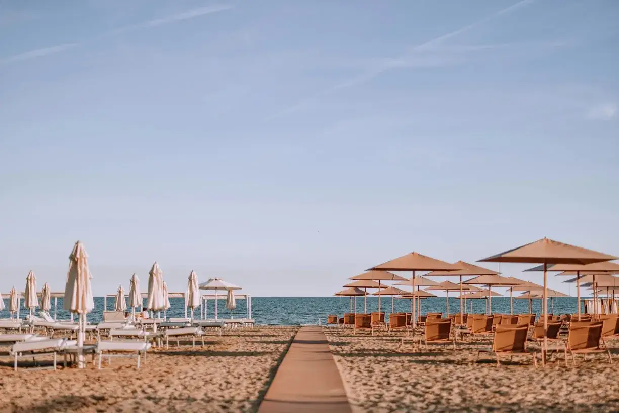 Ombrelloni e lettini pronti per accogliere i bagnanti su una spiaggia libera baciata dal sole.
