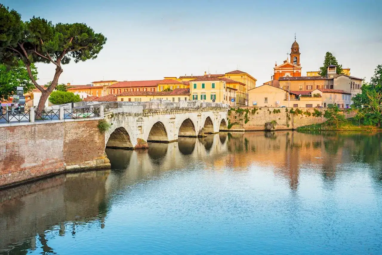 Ponte di Tiberio a Rimini, con edifici storici e riflessi sull'acqua. Un luogo incantevole vicino al Parco Briolini.