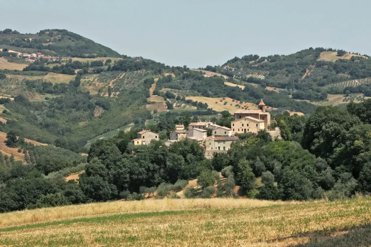 Borgo collinare di Cerreto di Saludecio con case in pietra e una chiesa, immerso nel verde della campagna romagnola.