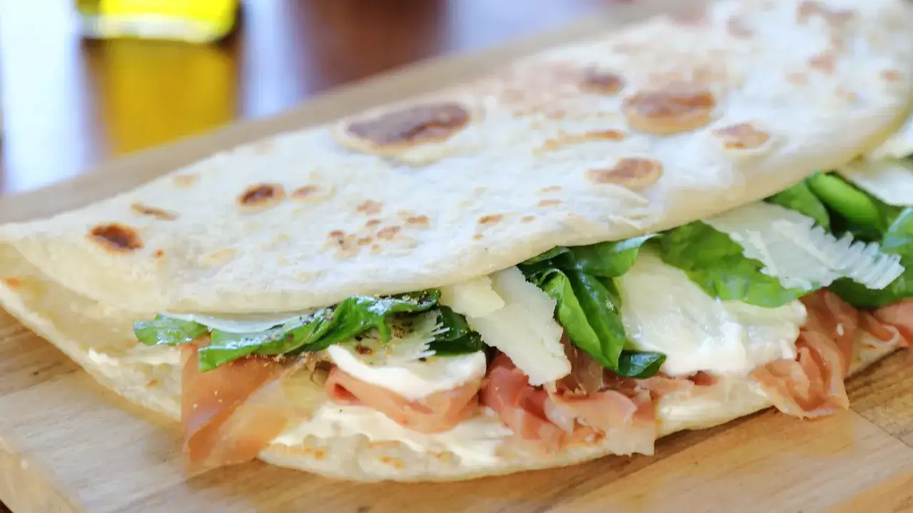 La piada, ripiena di prosciutto, mozzarella e rucola, evoca il sapore del mare e della terra.