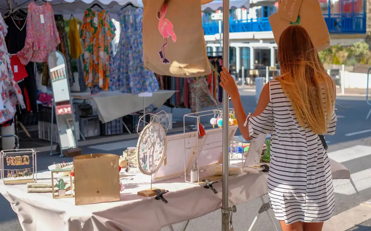Bancarella di abbigliamento e bigiotteria a Cesenatico centro negozi. Una ragazza osserva i prodotti.
