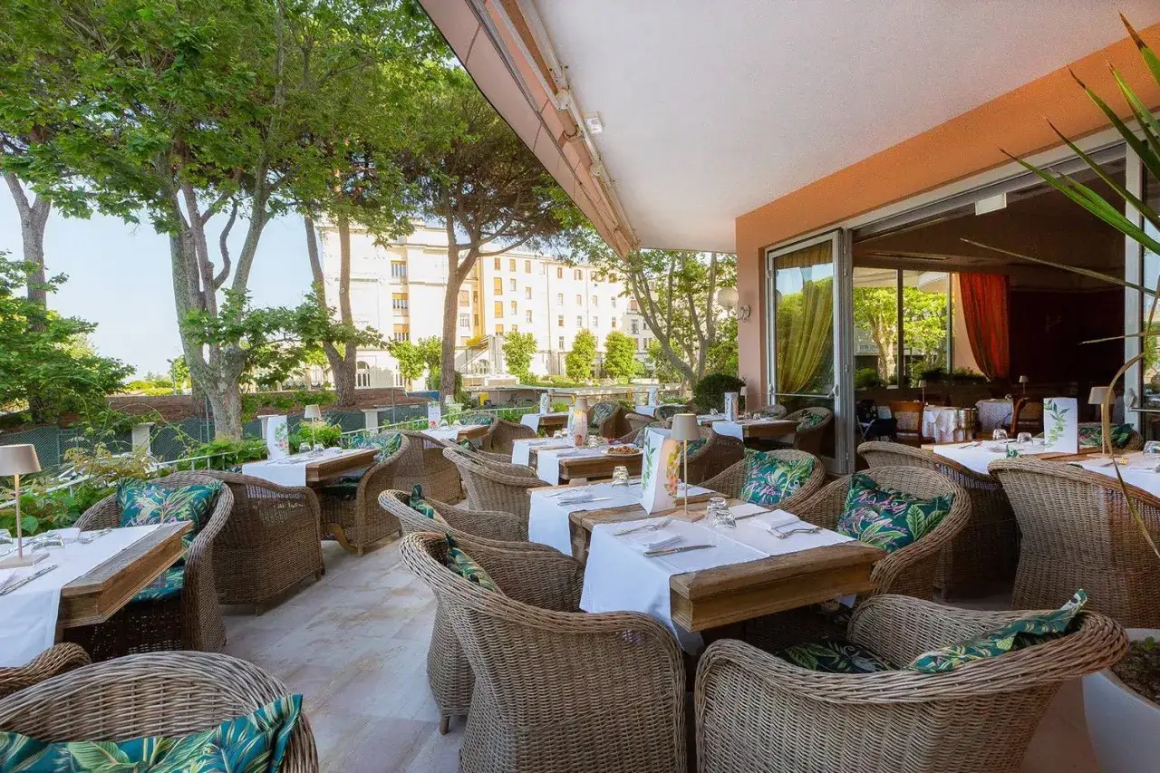 Terrazza elegante con tavoli apparecchiati e sedie in vimini, ideale per gustare le prelibatezze dei ristoranti stellati Rimini.