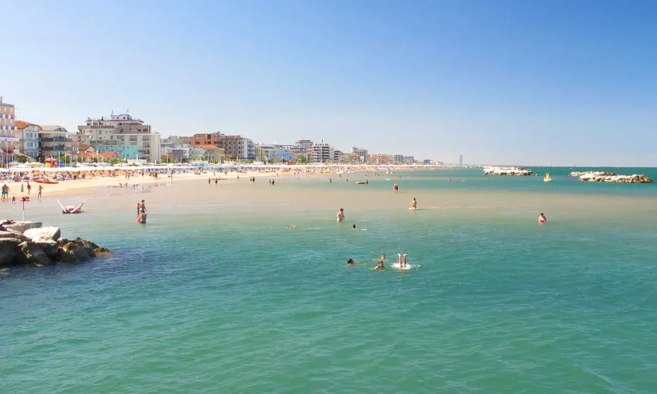 Una giornata di sole a Bellaria Mare, con bagnanti che si godono il mare cristallino e la spiaggia affollata di ombrelloni.