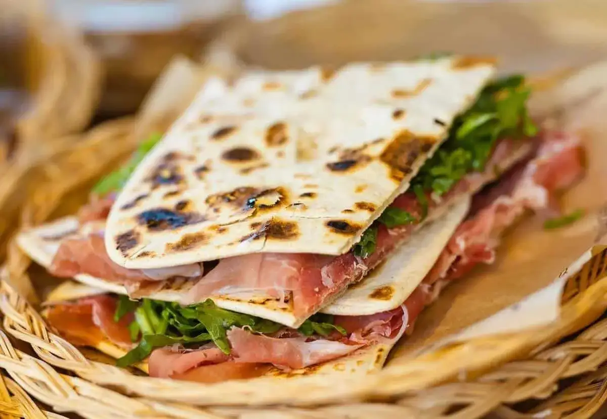 Piadina romagnola con prosciutto crudo e rucola, un classico del Rimini food da gustare in riva al mare.