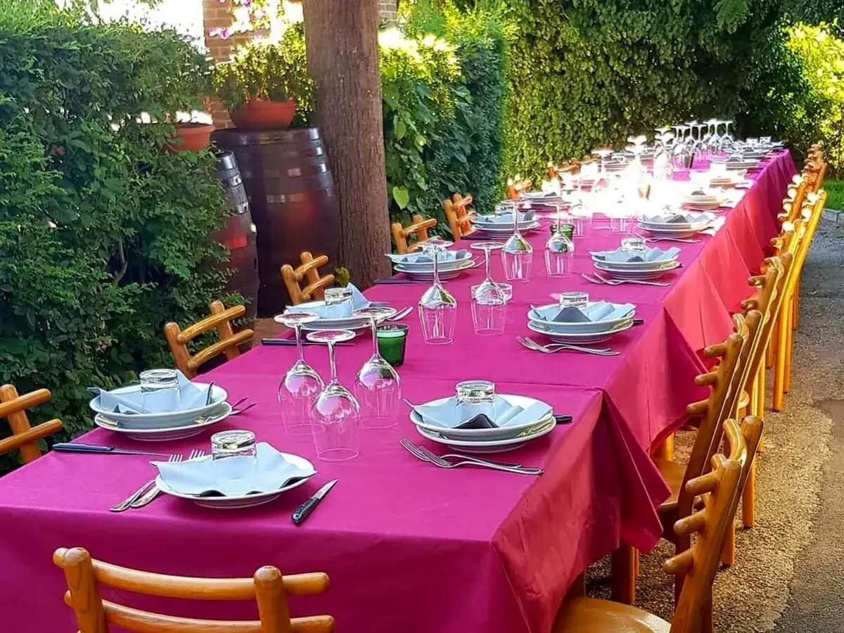 Tavola apparecchiata per una festa all'osteria de borg, con tovaglie fucsia, bicchieri e piatti pronti per gli ospiti.