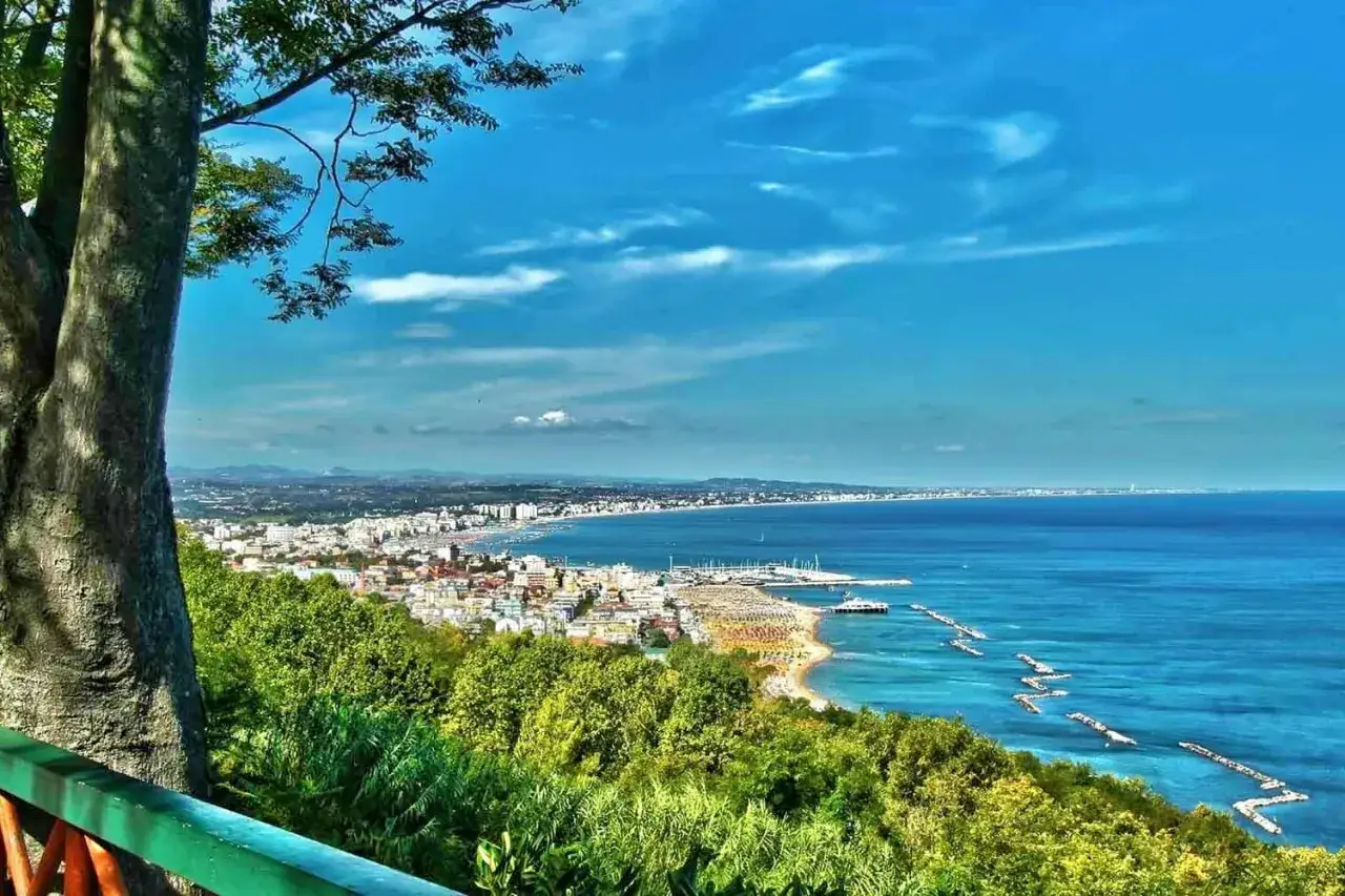 Vista panoramica del mare della riviera adriatica con una città costiera e una spiaggia affollata.