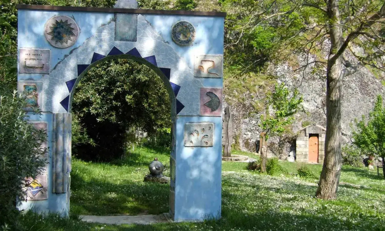 Arco decorato con mosaici e ceramiche, immerso nel verde di un giardino a Pennabilli, Rimini.