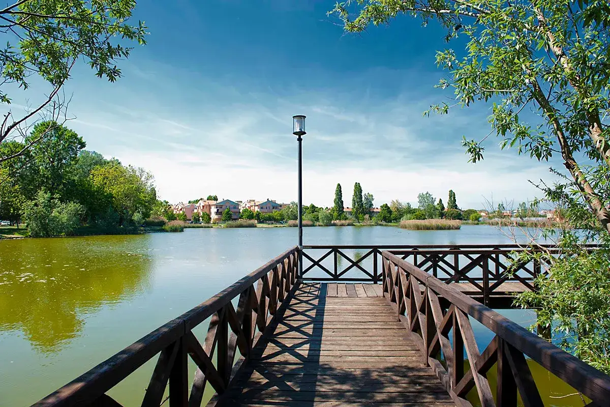 Molo in legno su un lago tranquillo, con case sullo sfondo. Un posto sereno, ma meglio Bellaria o Igea Marina per la vacanza?
