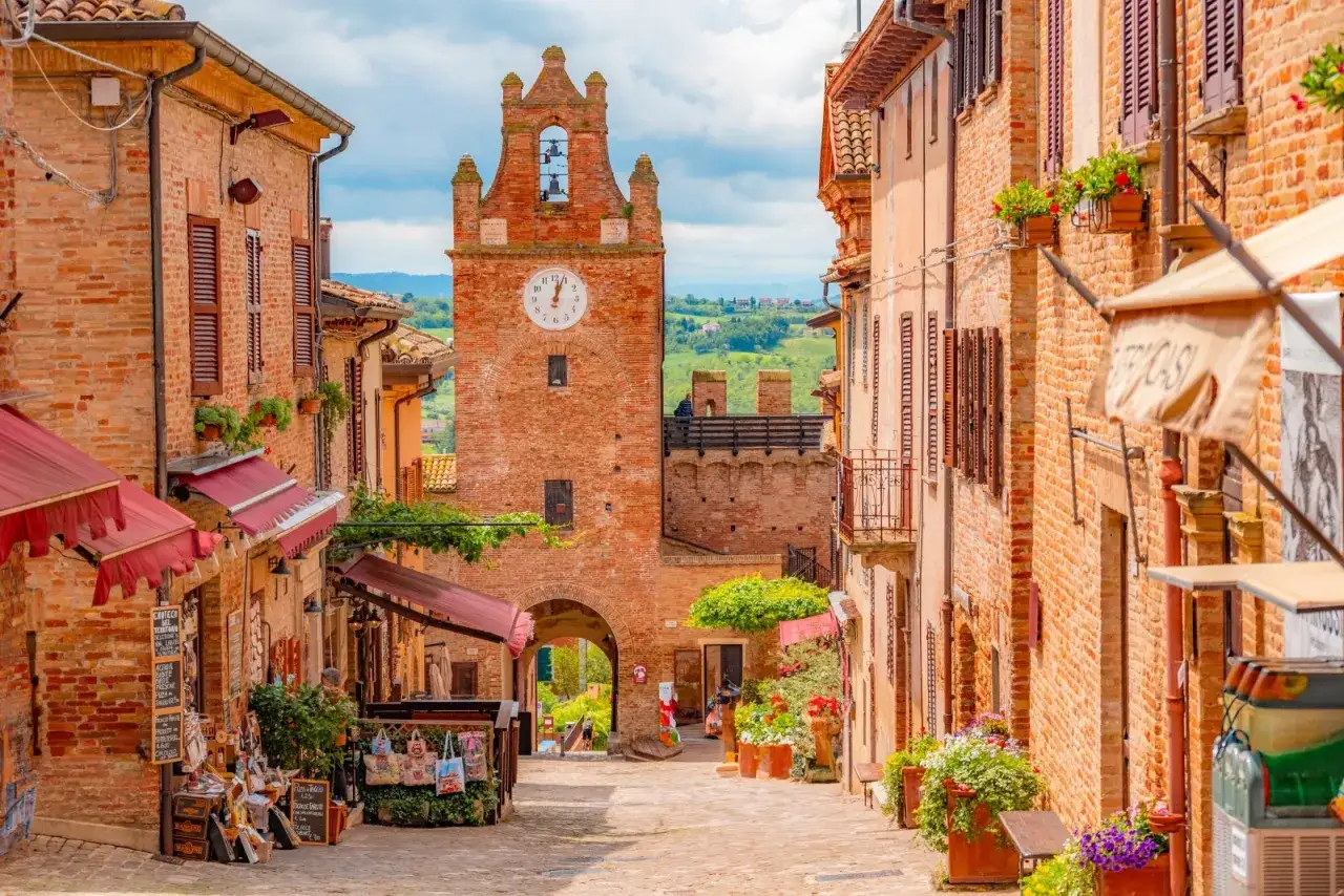 Borgo medievale con torre dell'orologio, negozietti e fiori. Un'ottima meta per scoprire cosa vedere vicino a Gradara.