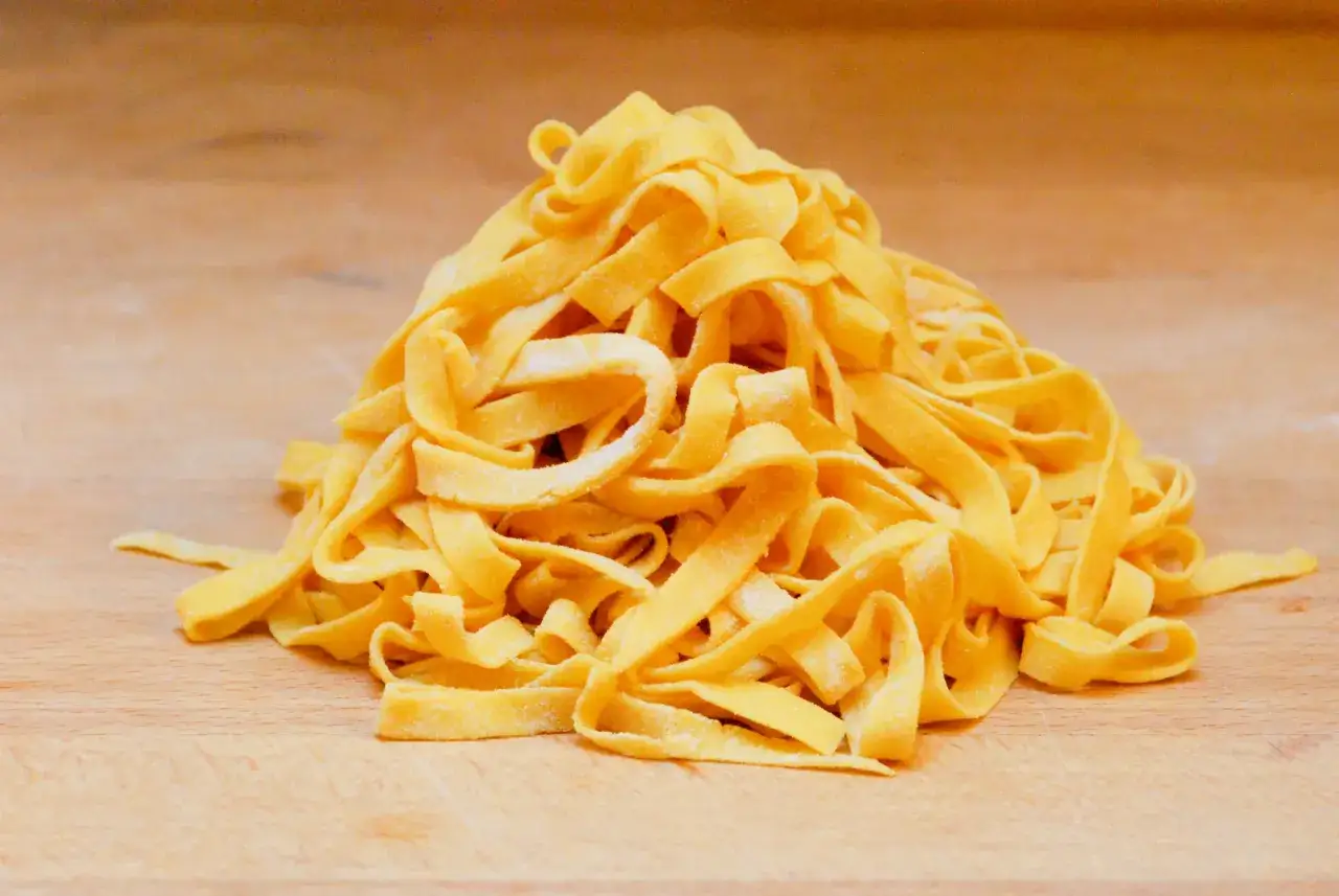 Fettuccine fresche su tagliere di legno, pronte per essere gustate in una trattoria Rimini centro.