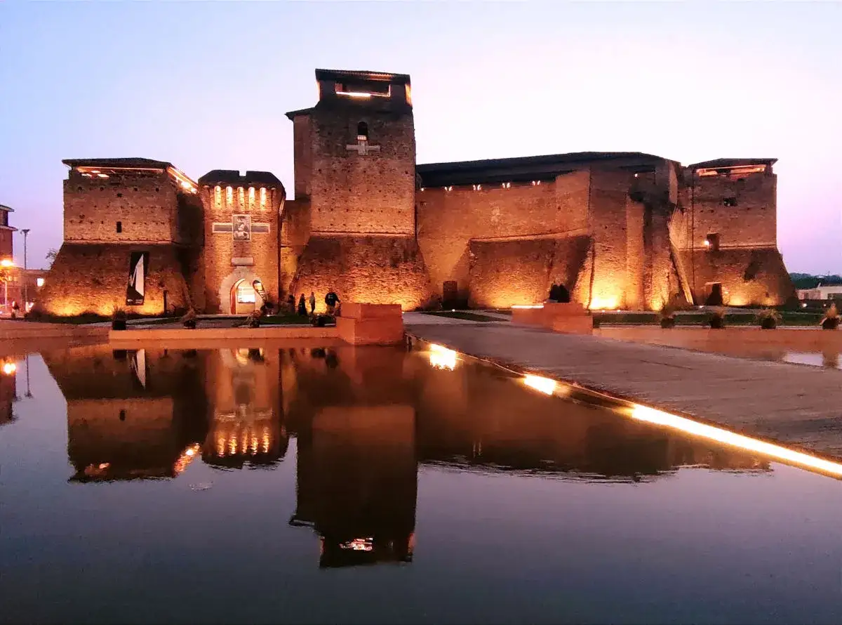 Castello Sismondo illuminato di sera, con riflessi sull'acqua. Un luogo che evoca la magia del cinema, come un museo felliniano a Rimini.