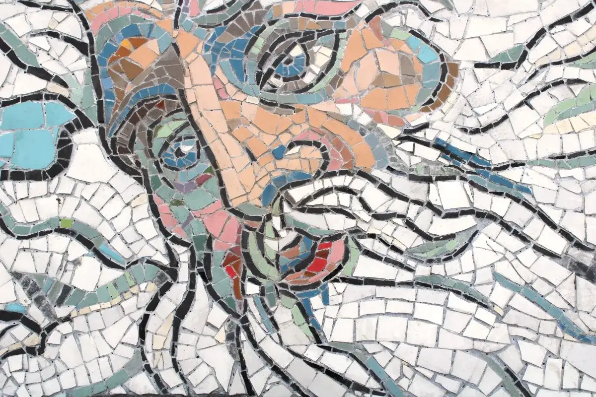 Un volto stilizzato in mosaico, un'opera di street art a Ravenna, con colori vivaci e linee dinamiche.