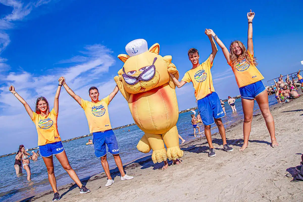 Giovani animatori con un gonfiabile a forma di gatto festeggiano sul lungomare di Gatteo Mare.