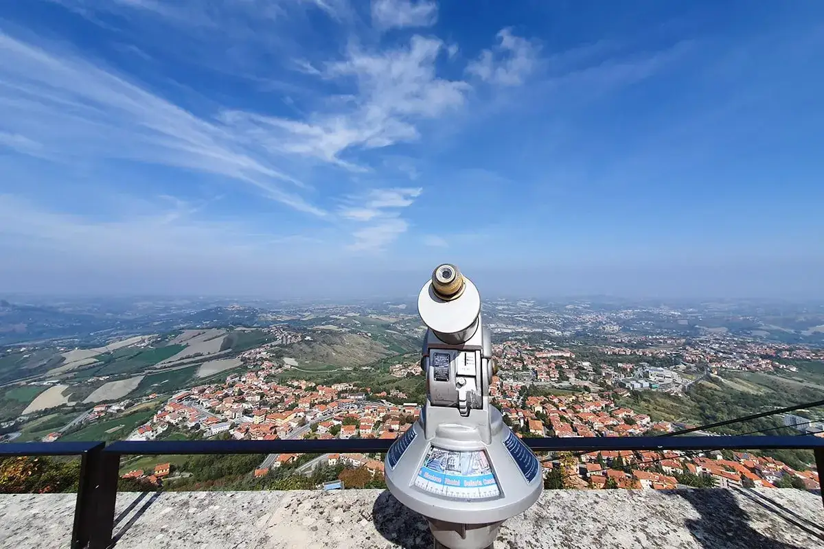 Telescopio pronto per ammirare il panorama mozzafiato del san marino centro, con le sue case dai tetti rossi e le colline verdi sotto un cielo azzurro.