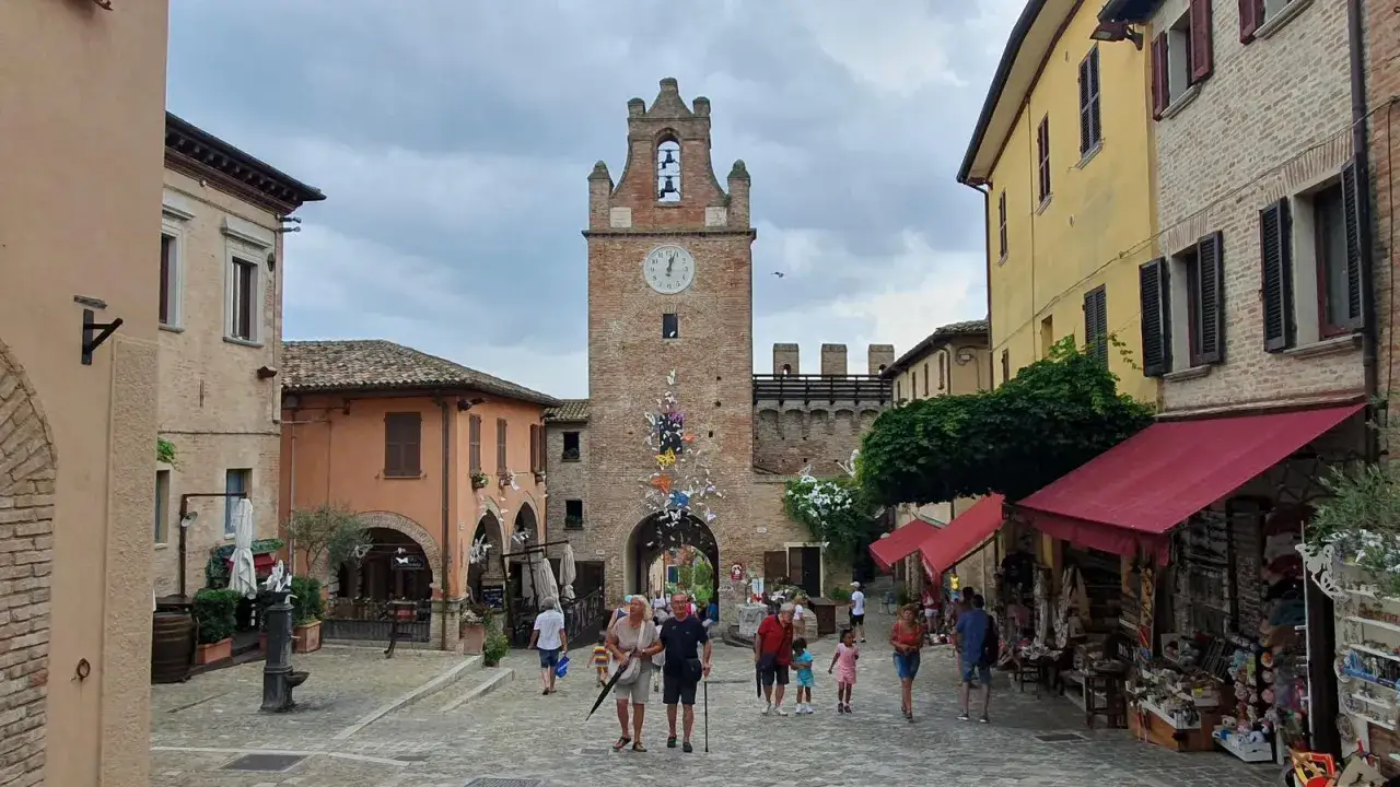 Un borgo incantevole, perfetto per scoprire cosa visitare a Cattolica. Una piazza con un torre antica, negozietti e gente che passeggia.